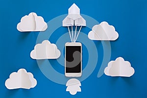 Start up or fast connection concept. The launch paper rocket with smart phone on blue sky with clouds.