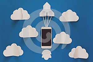 Start up or fast connection concept. The launch paper rocket with smart phone on blue sky with clouds. Origami. Paper cut.