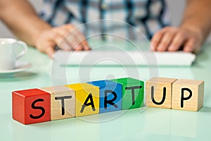 Start Up inscription on colored blocks, in the background a man leaning over the computer, concept, modern approach to business,