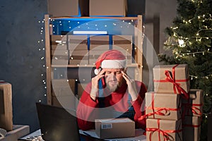 Start up small business entrepreneur SME man in Santa hat working with box at home, frustated stressed small business
