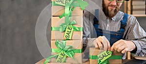 start-up small business owner freelancer in leprechaun hat packing boxes for delivery to customer hangs sale