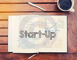 Start Up : text inside notebook on table with coffee
