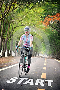 Start word and woman ride bike on road with tree tunnel