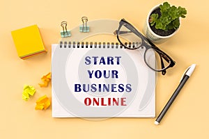 START YOUR BUSINESS ONLINE Text written on notepad page, glasses, pen, stationery on yellow background. conceptual image