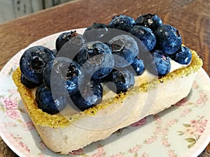 Start your day with homemade Gourmet pastry fresh blueberry cheese cake on vintage flora dish on wood table in cafe with blur back