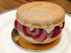 Start your day with homemade Gourmet pastry Macaron cream cheeses and raspberry on golden cake tray and white dish with blur backg