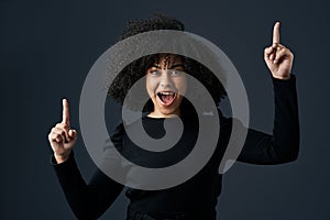 Started from bottom now were here. Shot of a young businesswoman pointing upwards against a studio background.