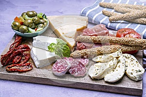 Starter with Cured meat and cheese traditional Spanish tapas - jamon serrano, cheese - served on wooden board olives and bread