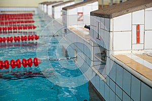 Starting blocks and lanes in a swimming pool. Edge of indoors sport swimming pool. Starting platforms with numbers