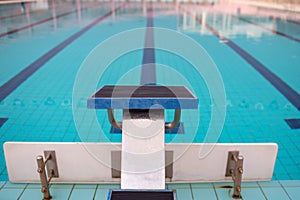 Starting blocks in row by the swimming pool, selective focus. Jump platform for swimming in swimming pool and grandstand backgroun