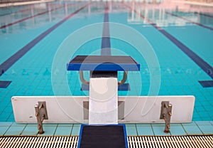 Starting blocks in row by the swimming pool, selective focus. Jump platform for swimming in swimming pool and grandstand backgroun