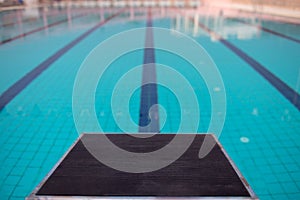 Starting blocks in row by the swimming pool, selective focus. Jump platform for swimming in swimming pool and grandstand backgroun