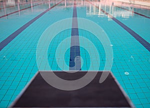 Starting blocks in row by the swimming pool, selective focus. Jump platform for swimming in swimming pool and grandstand backgroun