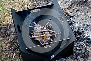 Starting the camp fire with kindling in a foldable firepit