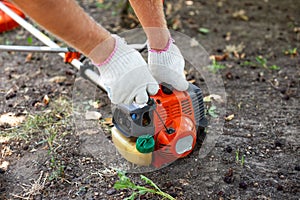 Starting a gas mower to mow grass. A man pulls the recoil starter to start the engine