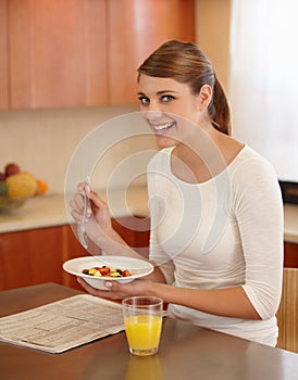 Starting her day with a fruit salad for breakfast. Portrait of a beautiful young woman eating her breakfast in the
