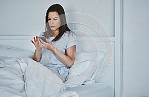 Starting her day with a quick text. an attractive young woman reading her text messages while lying in bed.