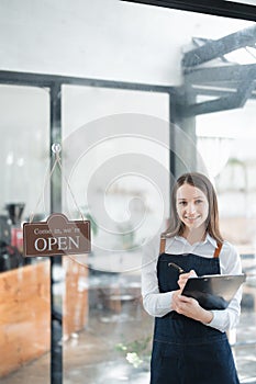 Starting and opening a small business, a young Asian woman showing a smiling face in an apron standing in front of a