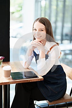 Starting and opening a small business, a young Asian woman showing a smiling face in an apron standing in front of a