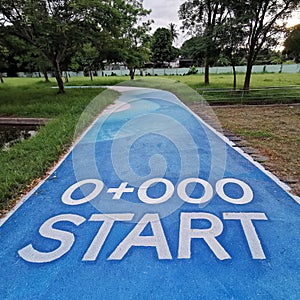 A starting position in running or jogging exercise lane in a public park, white paint on blue asphalt