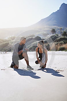 Starting their day out in the fresh air with some fitness. a sporty young couple tying their shoelaces while out for a