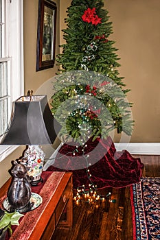 Starting to decorate the tree - Artificial Christmas tree with a few lights strung and others on wooden floor