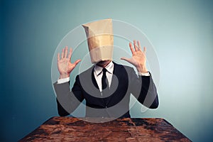 Startled businessman with bag over head raising his hands