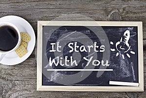 It Starts With You. Chalk board on a wooden table.