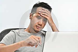 Startup business man holding his head looking stressed while working on a laptop