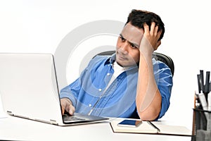 Startup business man holding his head looking stressed while working on a laptop