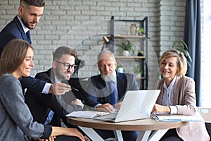 Startup business team on meeting in modern bright office interior and working on laptop