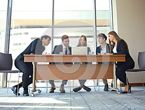 Startup business team on meeting in modern bright office interior and working on laptop.