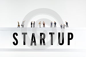 Startup concept. Miniature people on top of the lightbox with a word startup