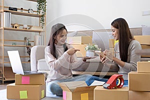 Startup small business owner working with computer at workplace. Freelance two woman seller check product order. Packing goods for