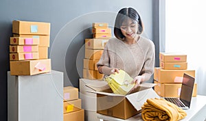 Startup small business owner working with computer at workplace. Freelance woman seller check product order. Packing goods for del