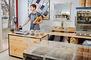 Startup small business people and service concept. Happy male small business owner stands at counter with cashbox in