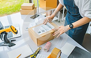 startup young female small business owners attaching shipping labels to cardboard boxes or parcels for delivery of customer orders