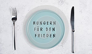 Starve for peace is standing in german language on the empty plate, food shortage because of the war in Ukraine, political issue