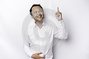 Starving Asian man wearing white shirt, pointing at the copy space on top of him, isolated by white background