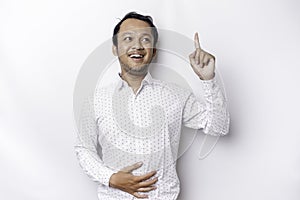 Starving Asian man wearing white shirt, pointing at the copy space on top of him, isolated by white background