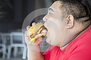 Starving obese man eating a big burger