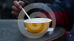 Starving poor man greedily eating hot soup from plastic bowl at homeless shelter