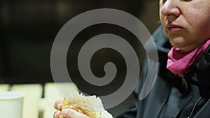 Starving poor woman eating large portion of junk food, biting burger greedily