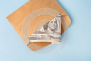 Stash of money in dollar bills coming out of an envelope on a blue background. The concept of salary, bribe, loan, debt, win