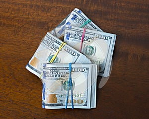 Stashes of hundred dollar bills on wooden table