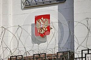 State coat of arms of Russia behind of barbed wire