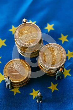 state of the economy in in European countries.Figures of men in suits on euro coins on european union flags.Budgets and