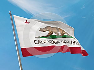 State flag of California flag on a pole waving. California realistic flag waving against clean blue sky.