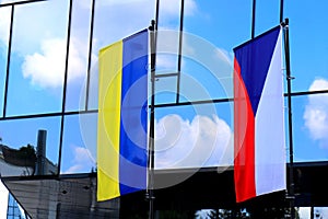 State flags of the Czech Republic and Ukraine near modern building in Prague. Czechs oppose Russia war against Ukraine, stand with photo