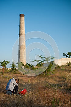 State of mind concept of small kid with head down near plant industrial factory after dismissal unemployment losing job